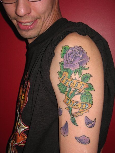 A man has a tattoo on his arm that says mom and dad