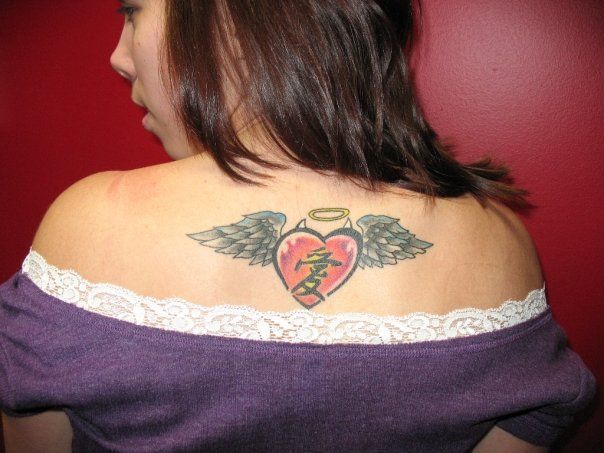 A woman has a tattoo of a broken heart with wings on her back