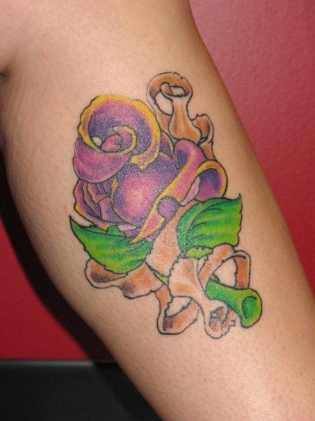 A woman has a tattoo of a rose on her leg