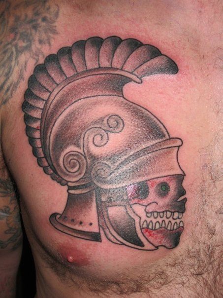 A man has a tattoo of a helmet and skull on his chest