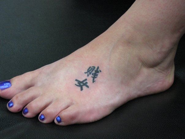 A woman with blue nails has a tattoo on her foot