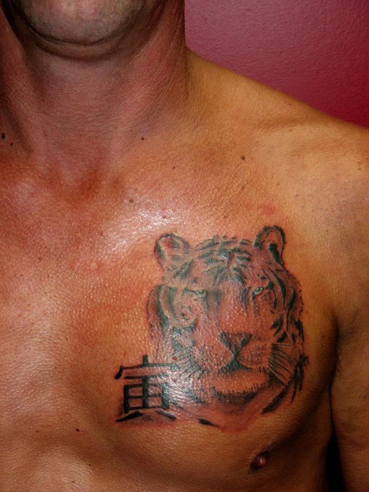 A man has a tattoo of a tiger on his chest.
