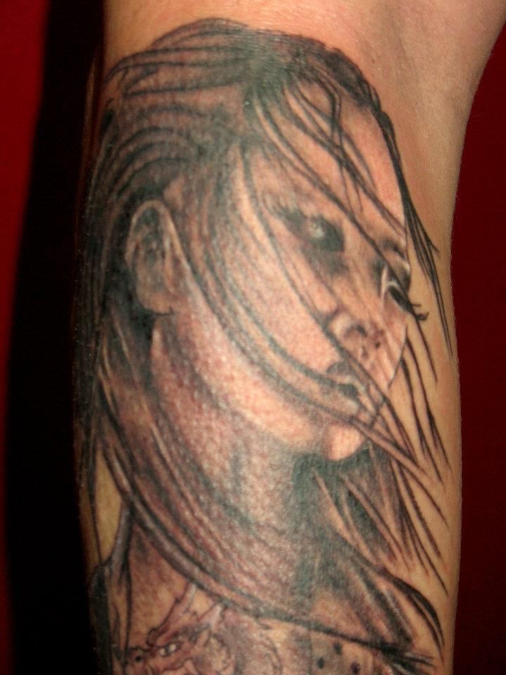 A man has a tattoo of a woman 's face on his leg.