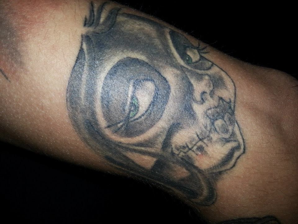 A close up of a tattoo of a skull on a person 's arm.
