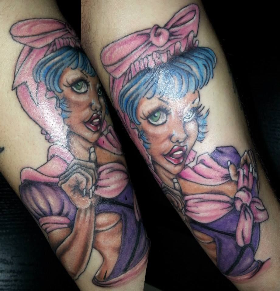 A tattoo of a woman with blue hair and a pink bow