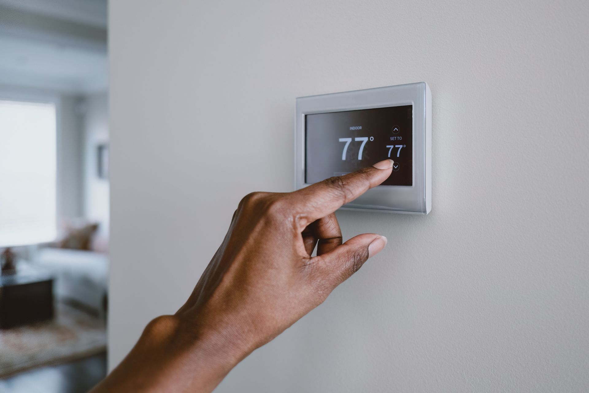 A person is adjusting a thermostat on a wall.