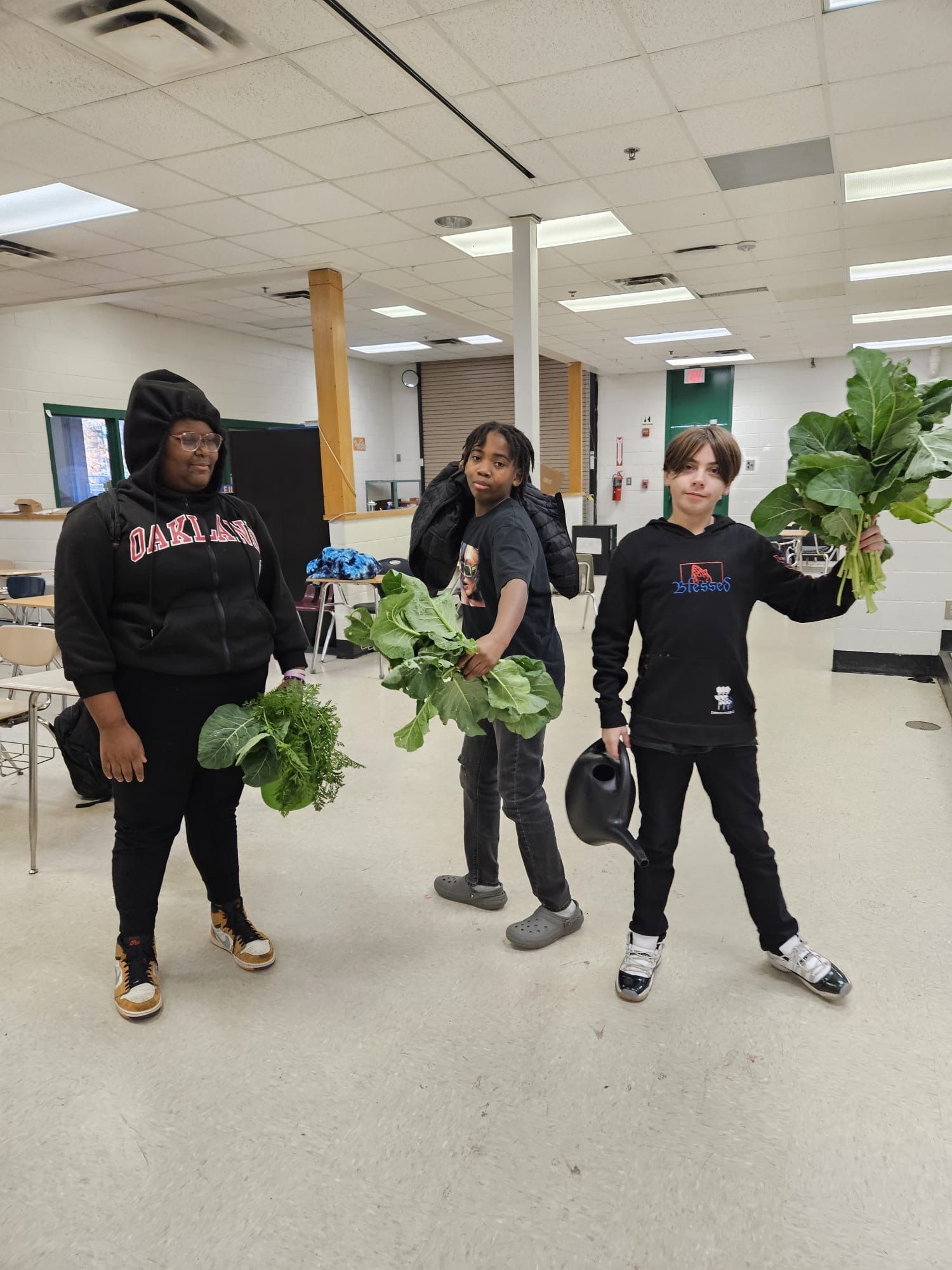 A group of people are standing in a room holding plants.