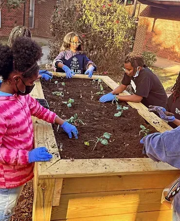 A group of children are working in a garden.