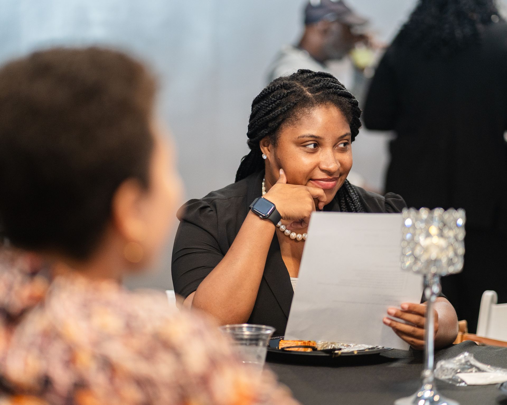 A woman is sitting at a table looking at a piece of paper.