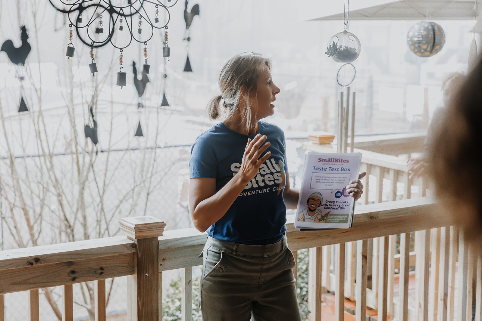 A woman is standing on a balcony holding a book.