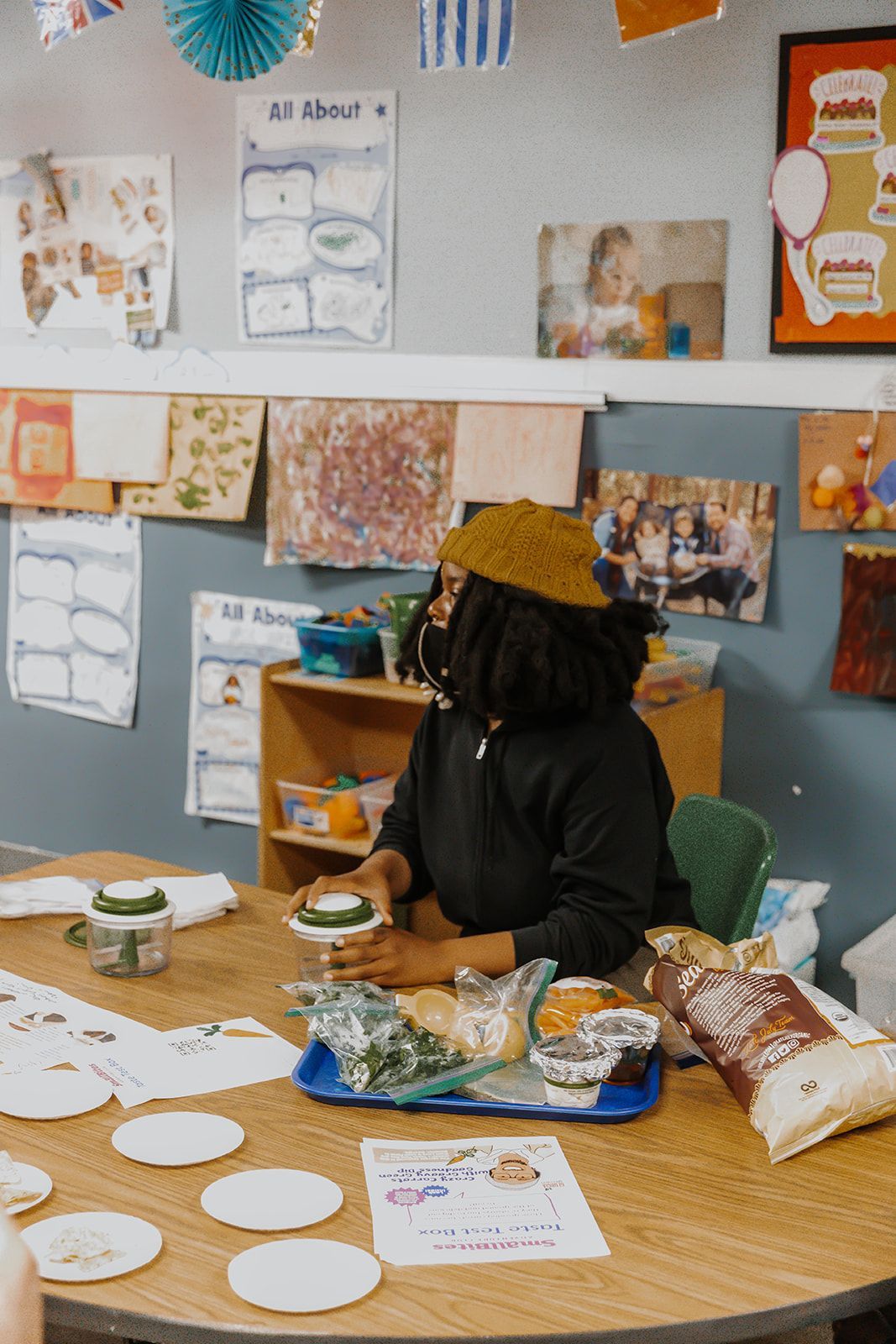 A woman is sitting at a table in a classroom holding a plate of food.