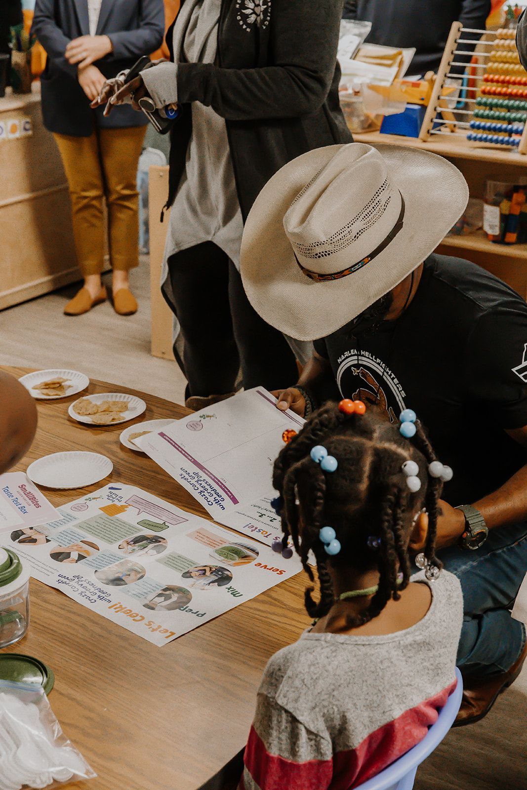 A man in a cowboy hat is sitting at a table with a little girl.
