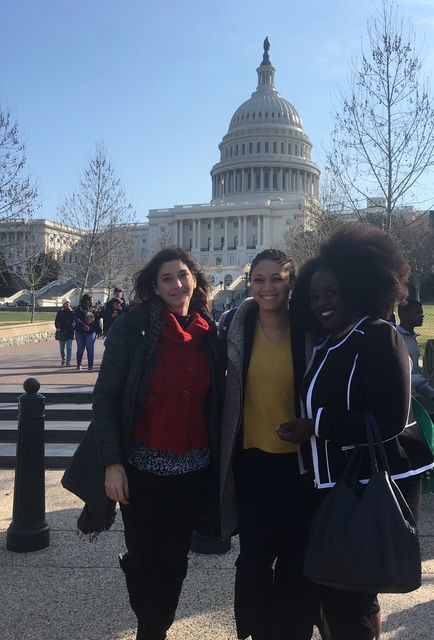 Three women are posing for a picture in front of the capitol building