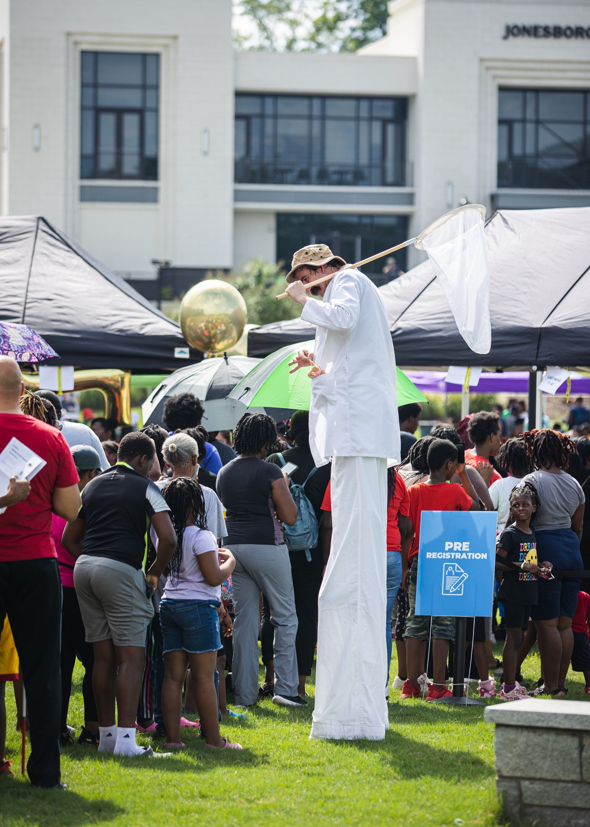 A man on stilts is standing in front of a crowd of people.