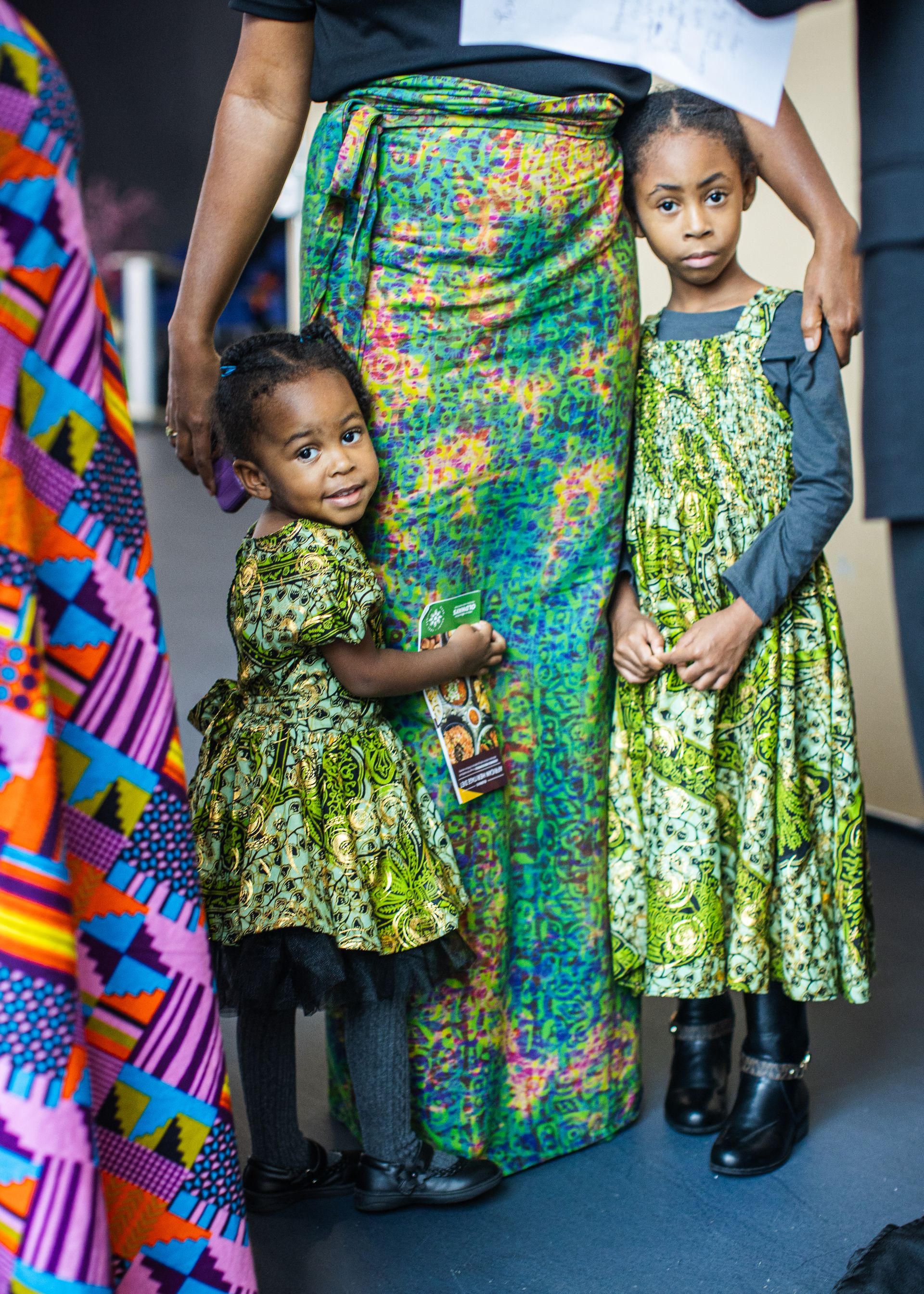 A woman is standing next to two little girls in matching dresses.