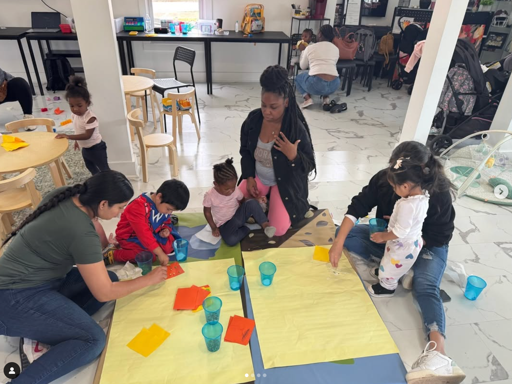 A group of children are sitting around a table in a room.