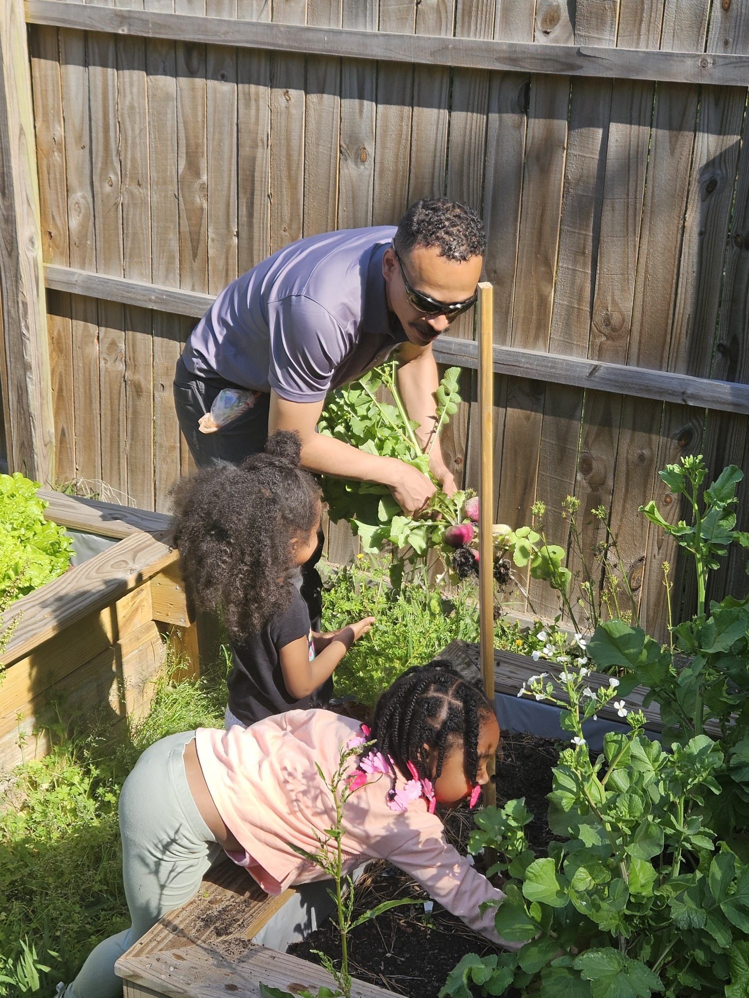 A man and two children are working in a garden