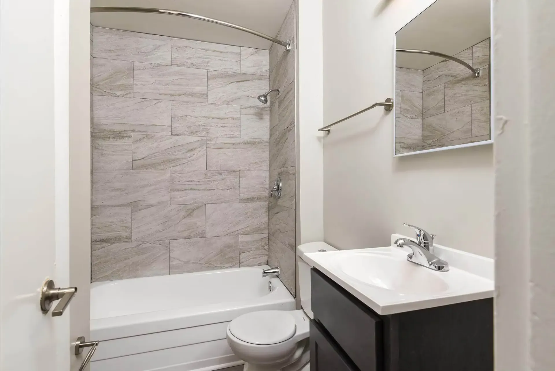 Apartment bathroom with tiled tub/shower surround, toilet, and vanity. Contact our leasing team at Harborstone Apartments today to schedule a tour of our studio, one-, and two-bedroom apartments in Newport News, VA. 