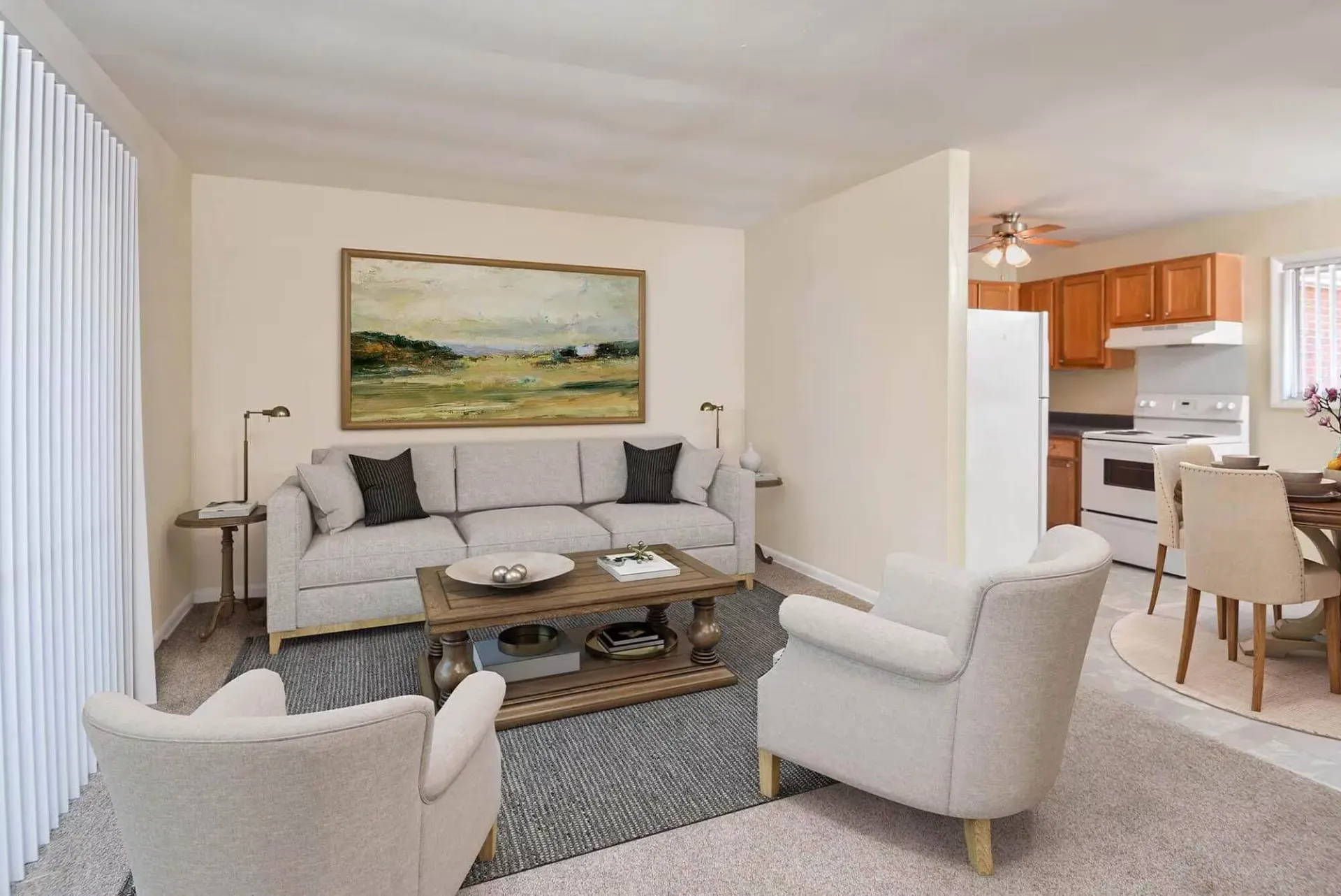 Living room interior with a gray sofa, two chairs, and a coffee table; open kitchen in background. Contact our leasing team at Harborstone Apartments today to schedule a tour of our studio, one-, and two-bedroom apartments in Newport News, VA. 