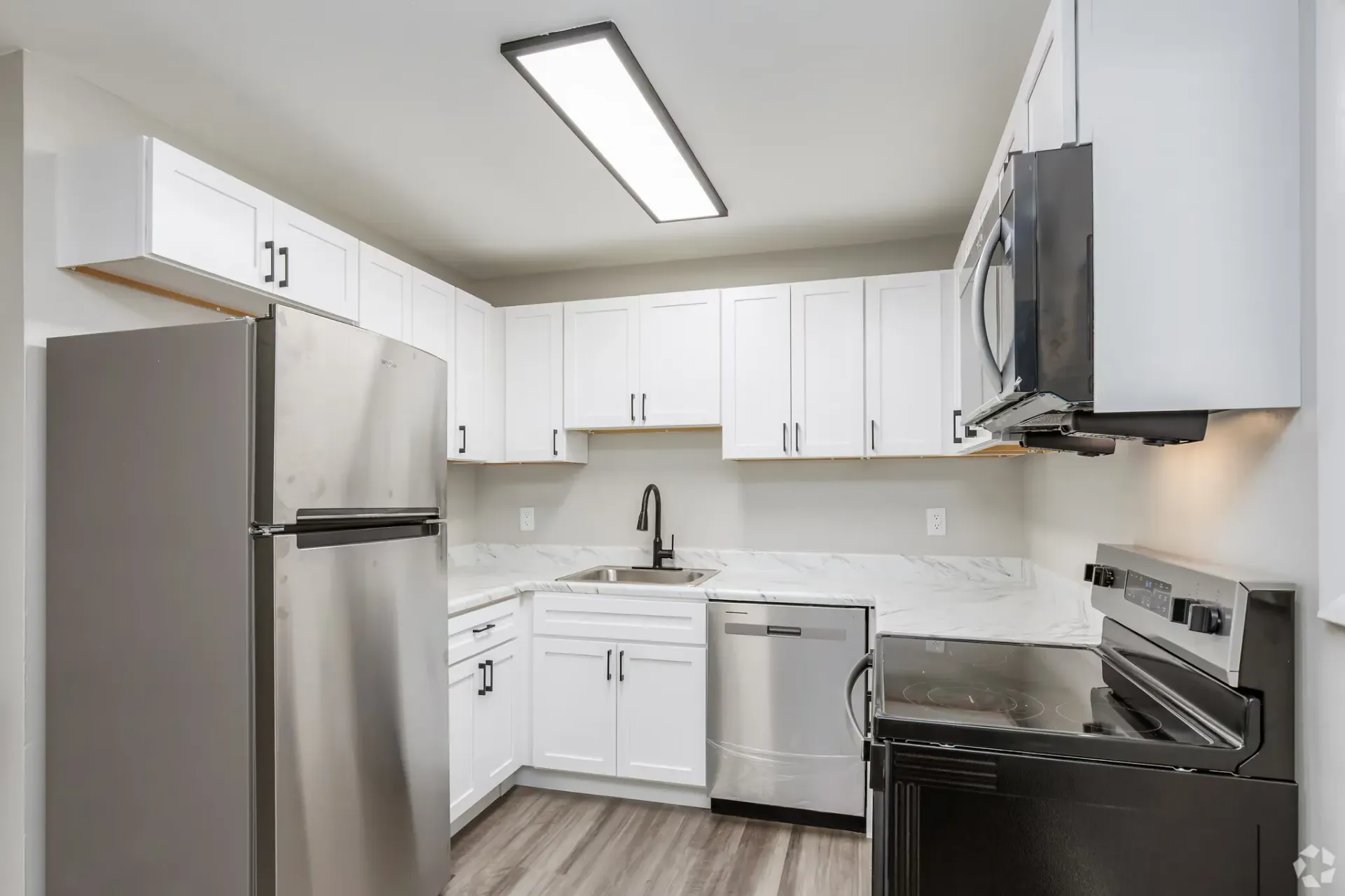 White kitchen with white cabinets, marble-look countertops, and stainless steel appliances. Contact our leasing team at Harborstone Apartments today to schedule a tour of our studio, one-, and two-bedroom apartments in Newport News, VA. 