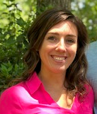 A woman in a pink shirt is smiling for the camera.