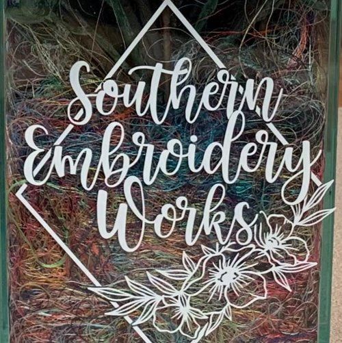 A sign that says `` southern embroidery works '' is on a window.