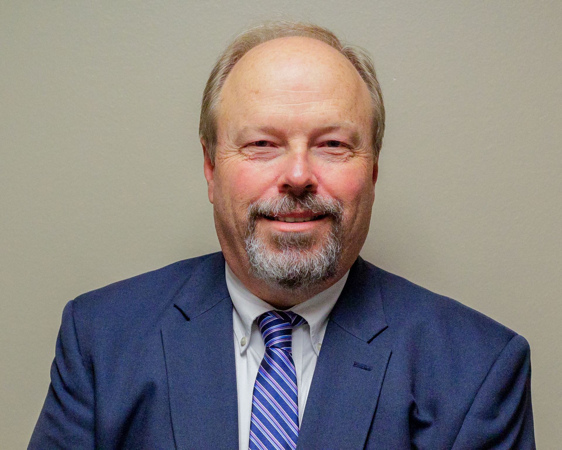 A man in a suit and tie is smiling for the camera.