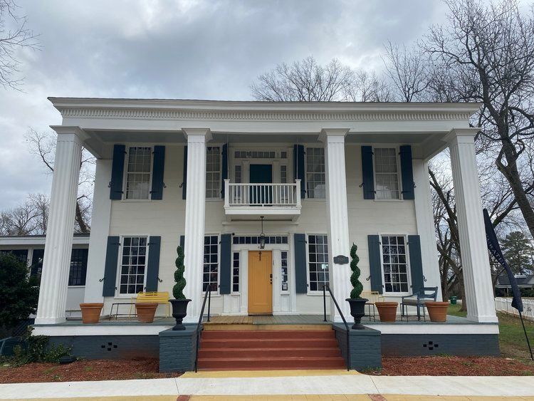 A large white house with black shutters and a balcony