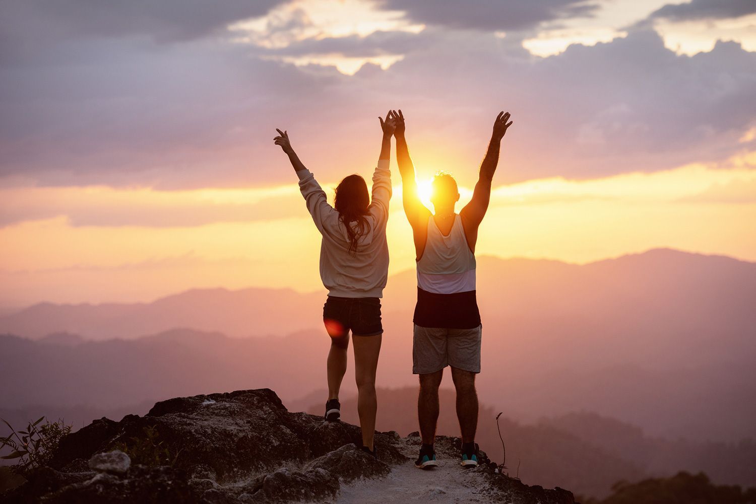 Couple Raising their Hands on Top of Mountain