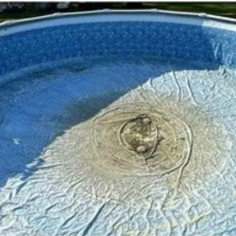 Collapsed above-ground pool liner with blue water and a large beige bulge in the center