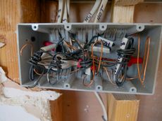 Electrical junction box crammed with tangled wires and wire connectors.
