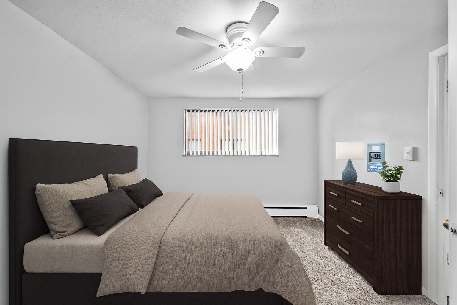 Bedroom with a bed, dresser, window, and ceiling fan. Neutral colors dominate.