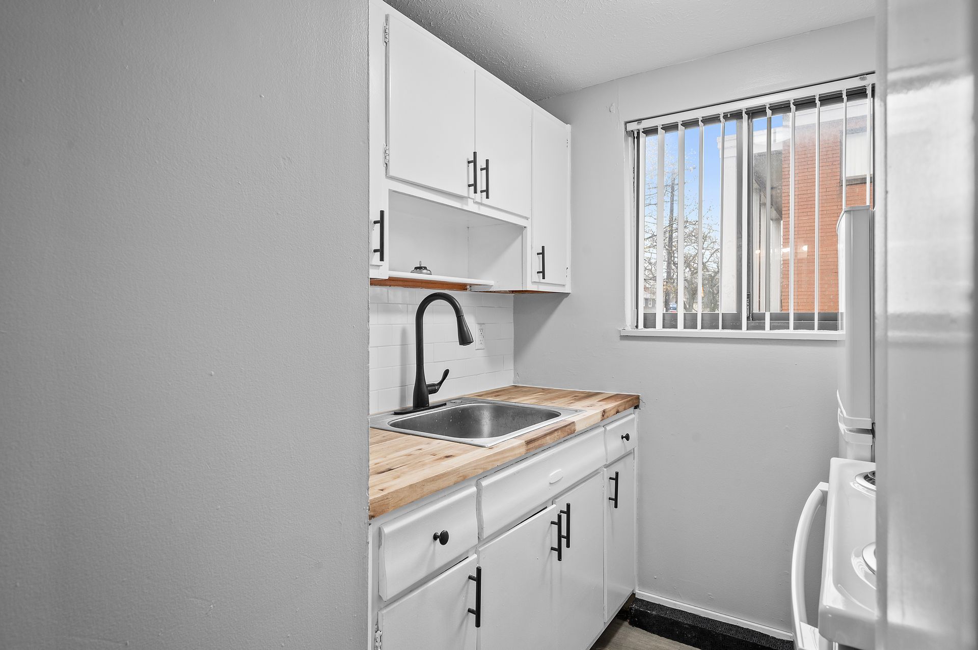 Small white kitchen with a window, cabinets, and sink.