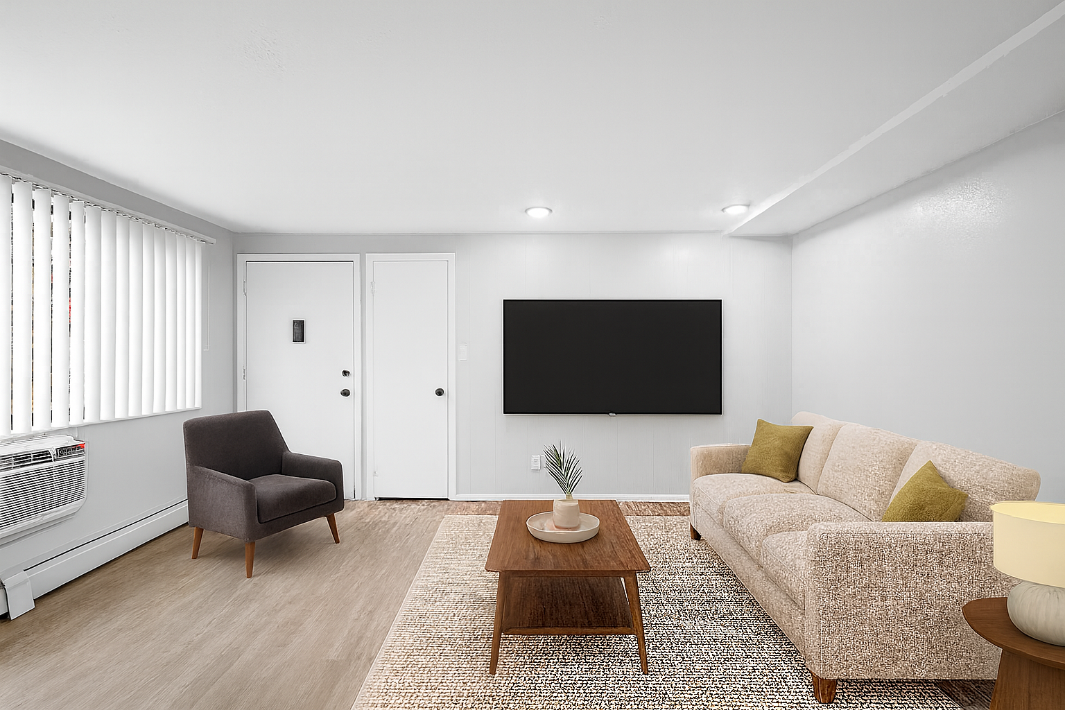 Living room with a couch, armchair, TV, and coffee table. Neutral colors, natural light.