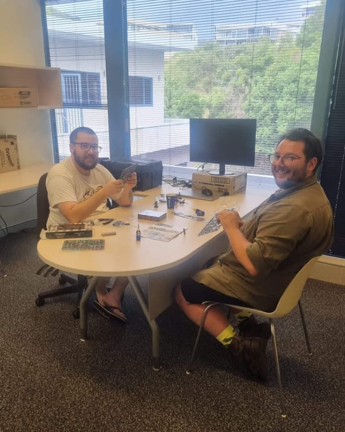Two Men Are Sitting At A Table In Front Of A Computer — Unique Life Services In Nelson Bay, NSW