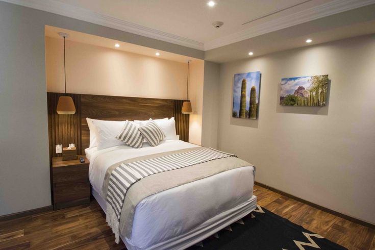 Una habitación de hotel con una cama tamaño king y dos mesitas de noche.