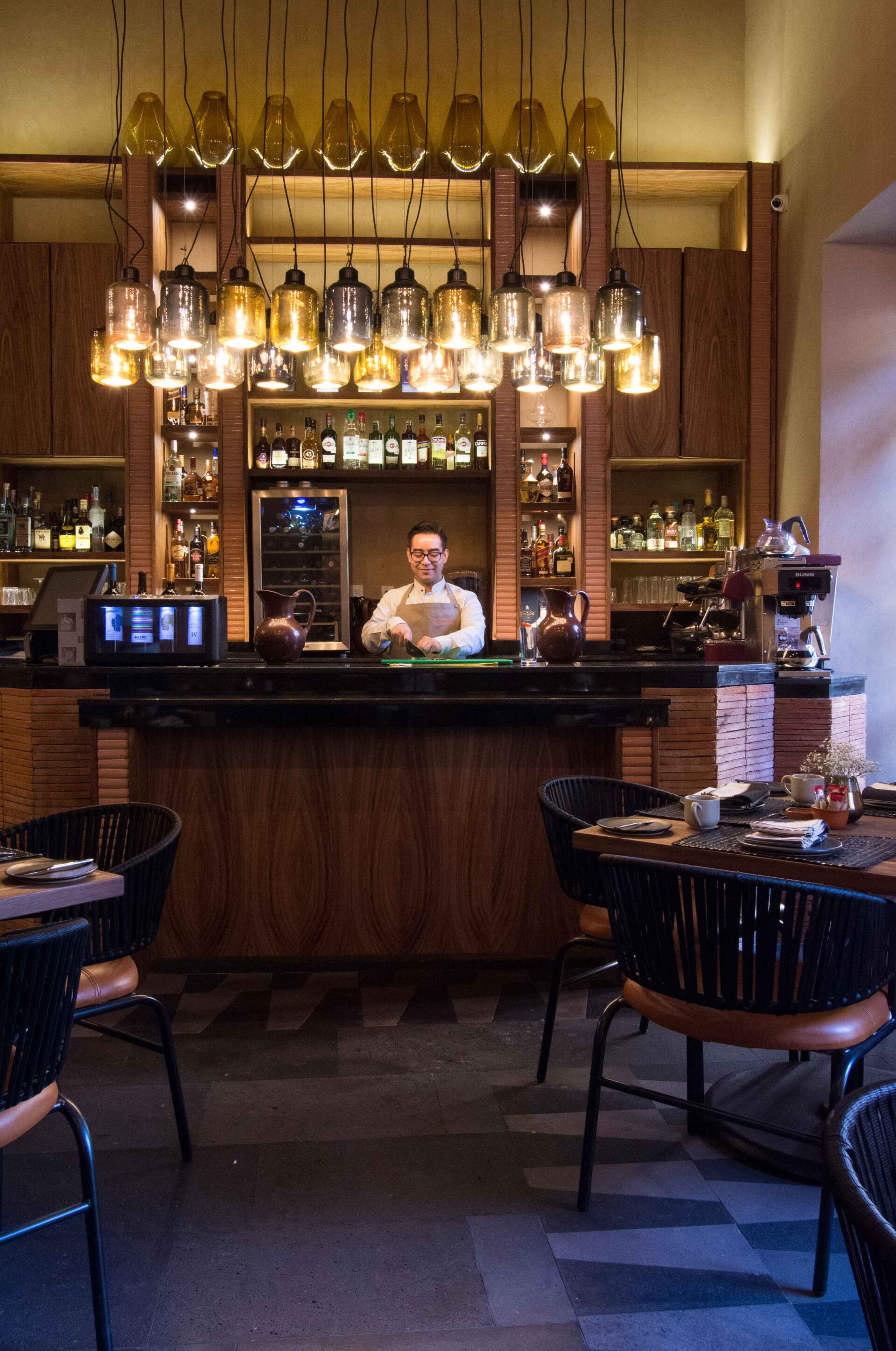 Un hombre está de pie detrás de una barra en un restaurante.
