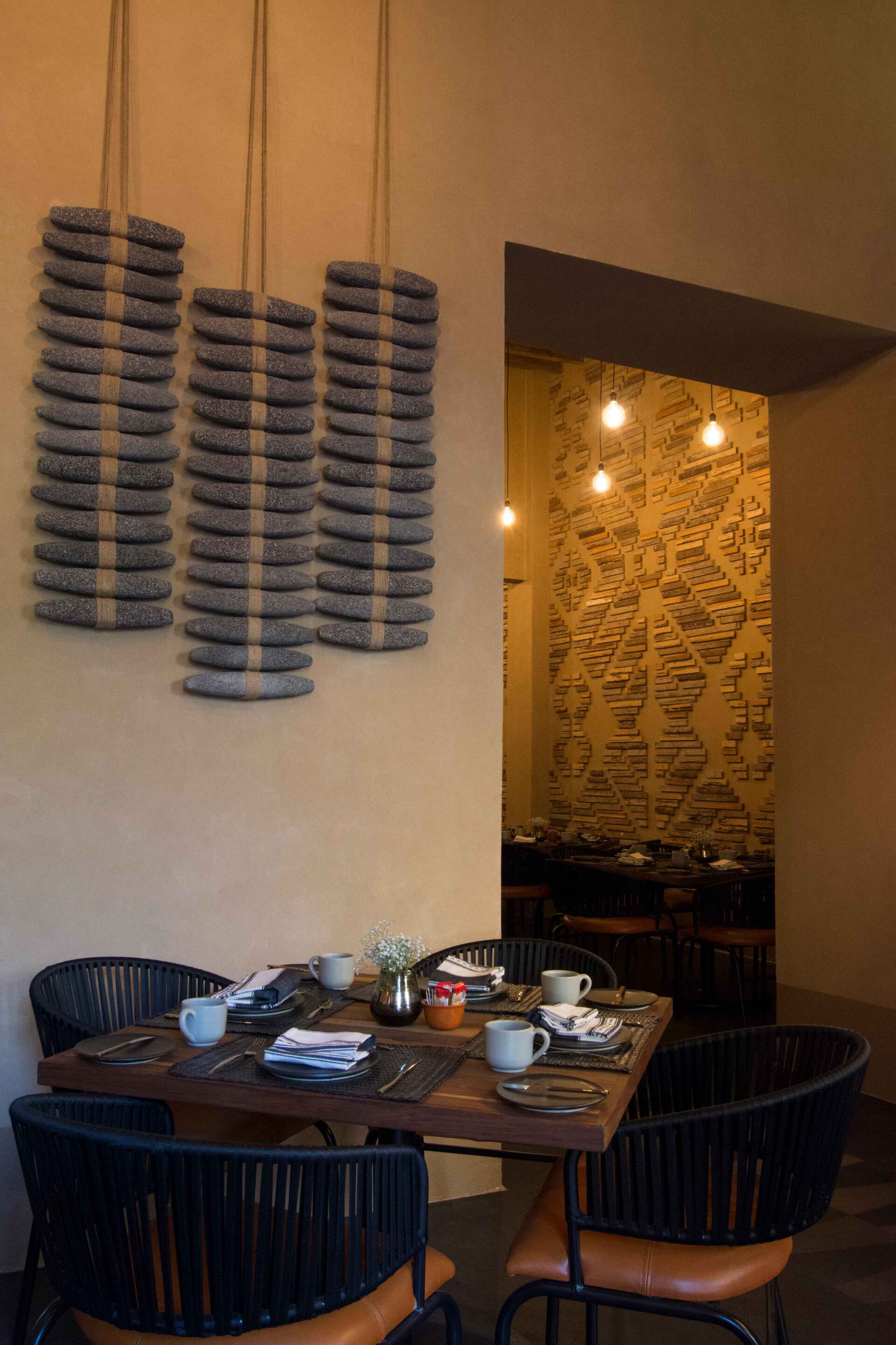 Un comedor con una mesa y sillas y una escultura colgante en la pared.