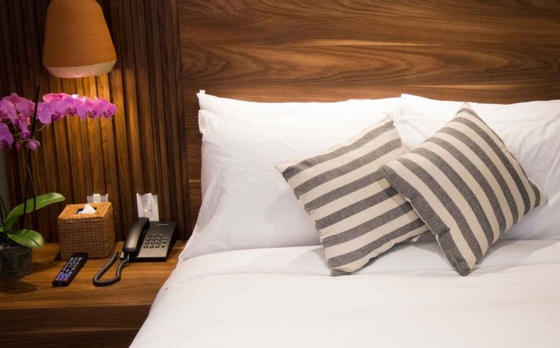 Una cama con sábanas blancas y almohadas a rayas en una habitación de hotel.