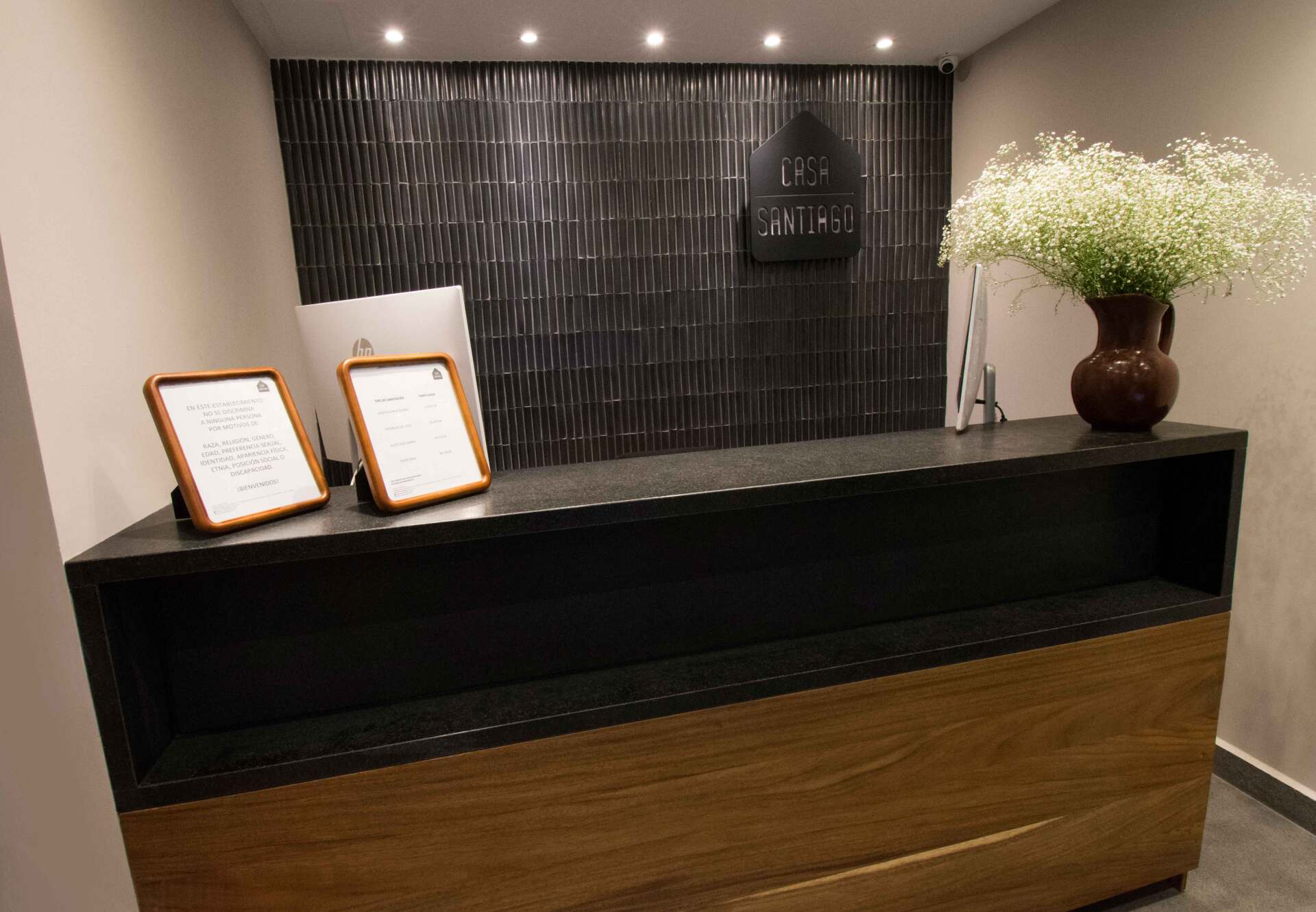 Un mostrador de recepción en un hotel con un jarrón de flores encima.