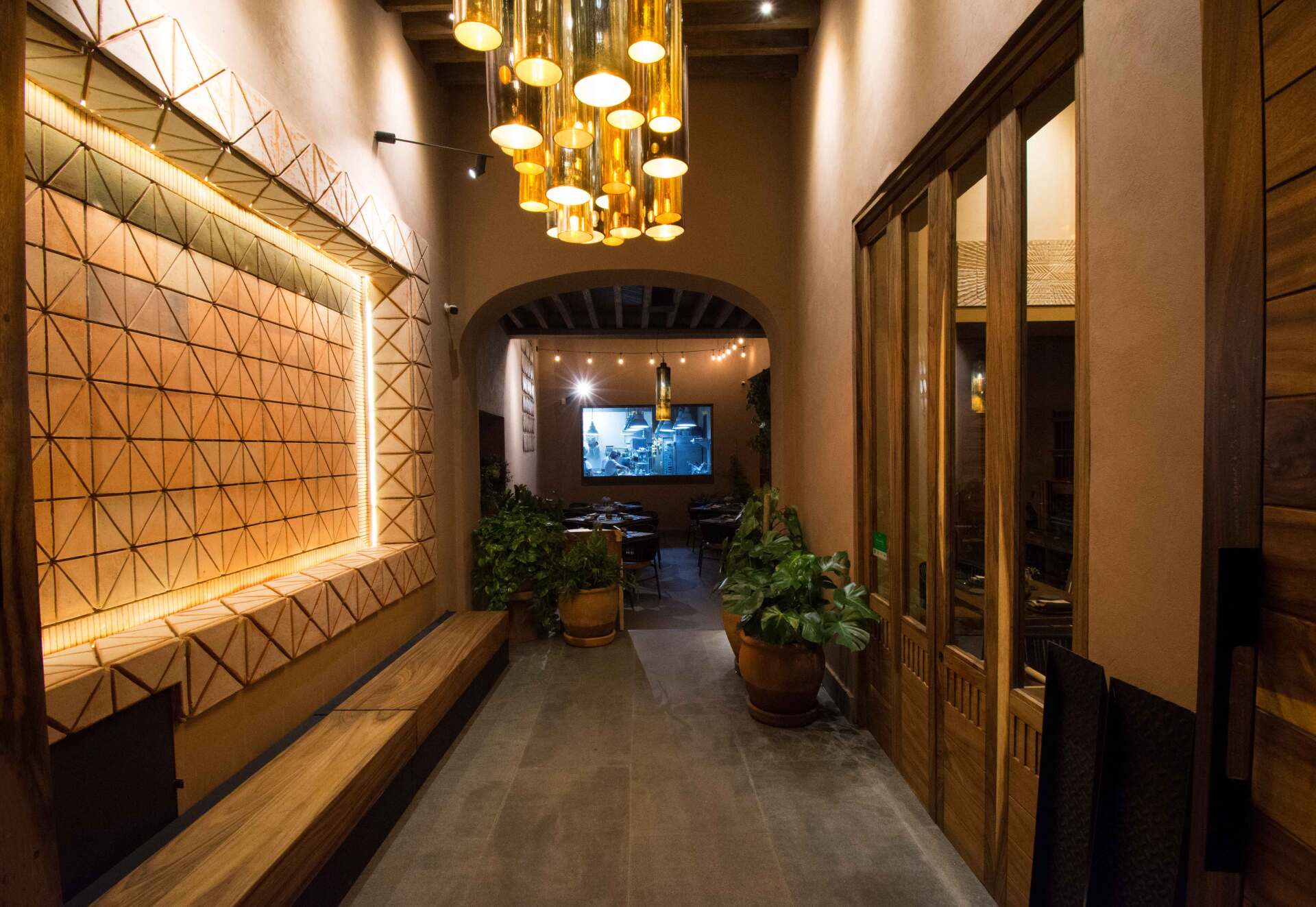 Un largo pasillo con un banco de madera y una gran pantalla en la pared.