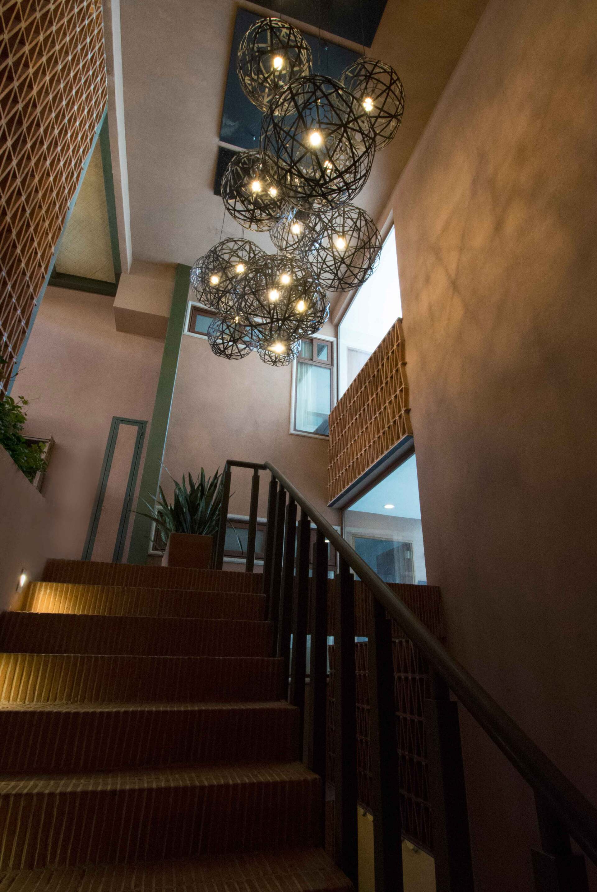 Una escalera con barandilla y una lámpara de araña colgando del techo.