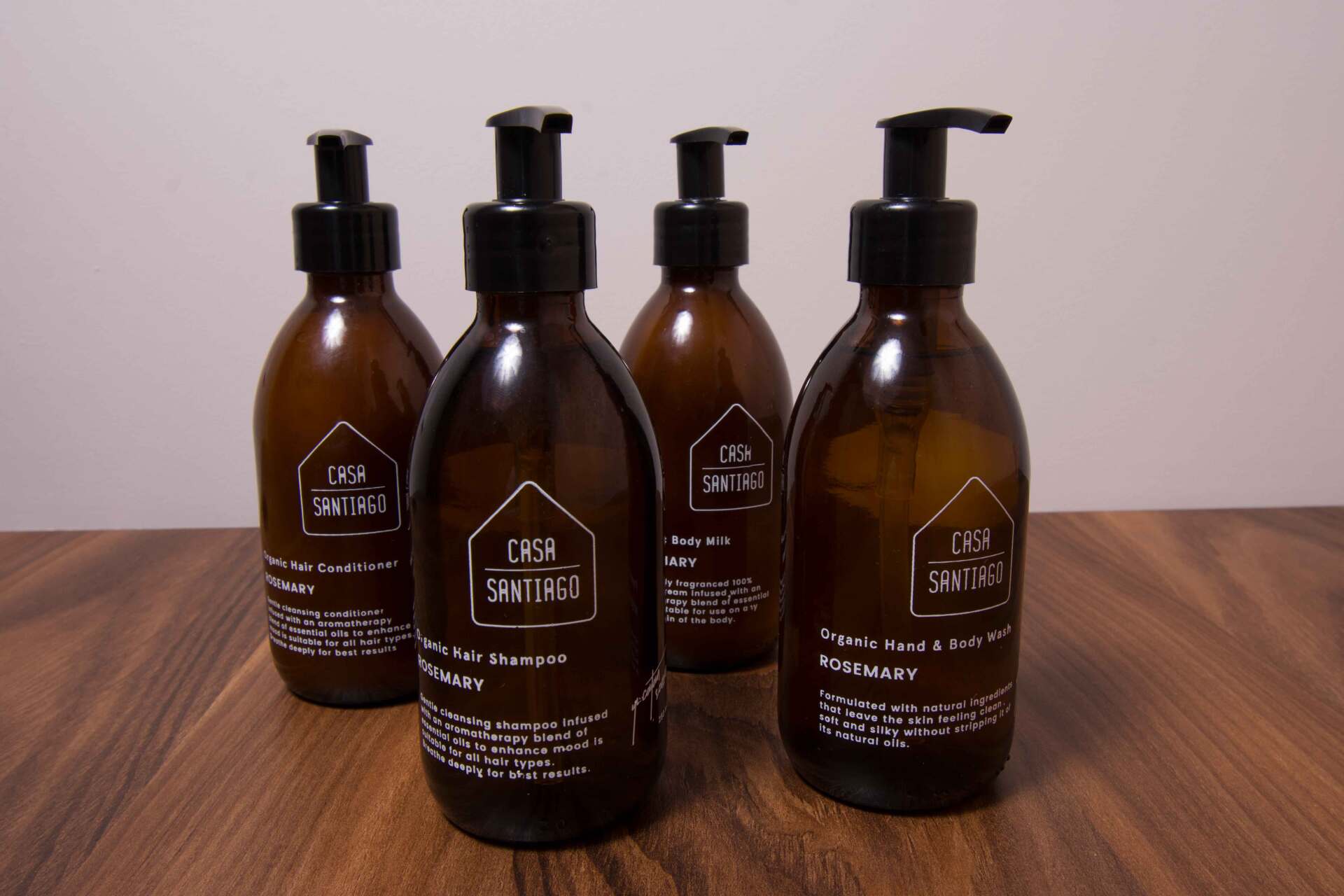 Cinco botellas de jabón están sobre una mesa de madera.