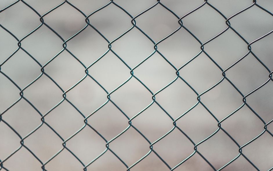 Chain-link fence with diamond-shaped openings. Blurred background.