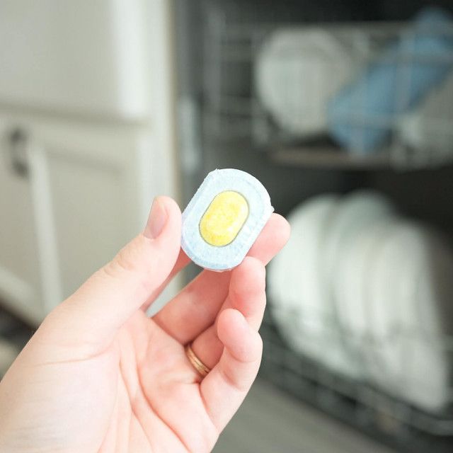 A bag of dishwasher tablets is sitting on a pink surface.