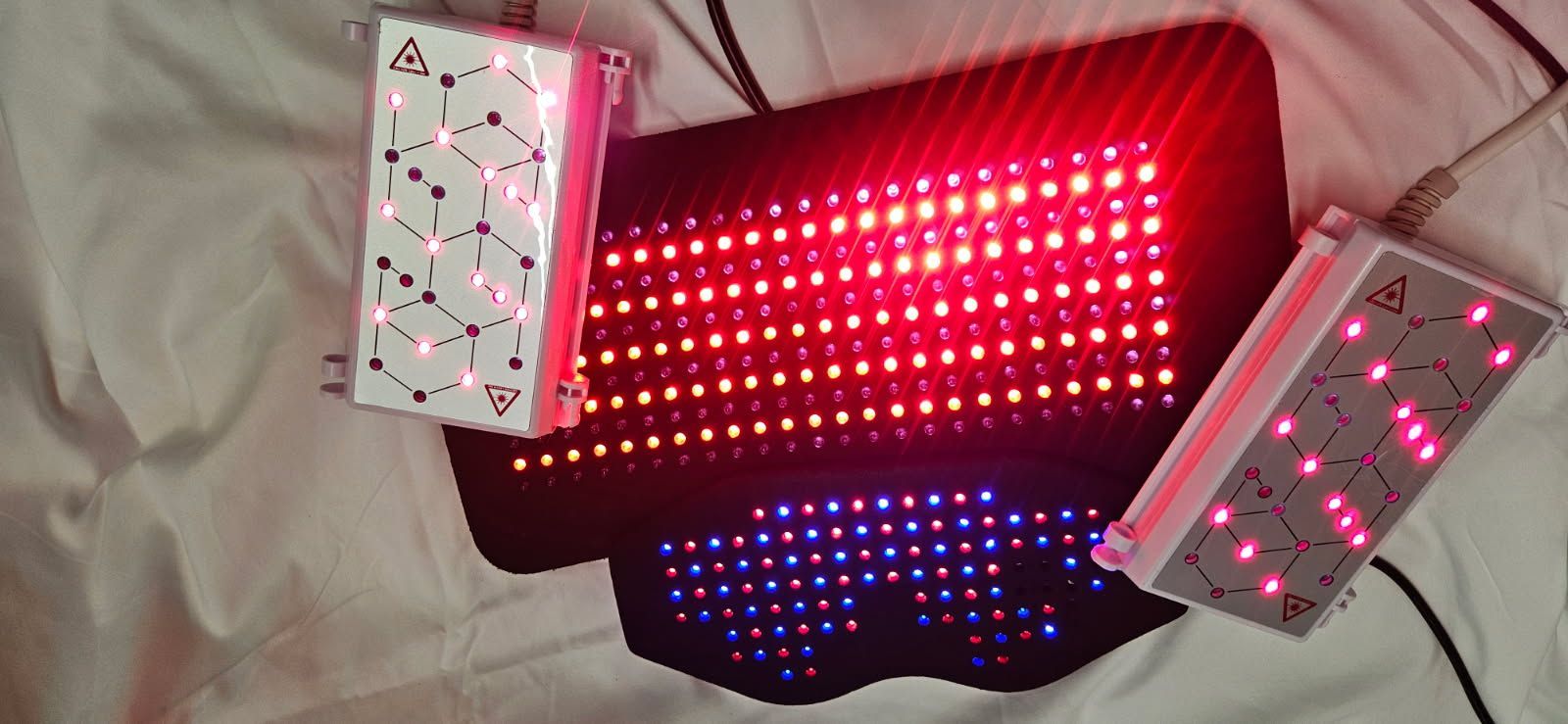 Red and blue LED light therapy device with two small controllers emitting red light.