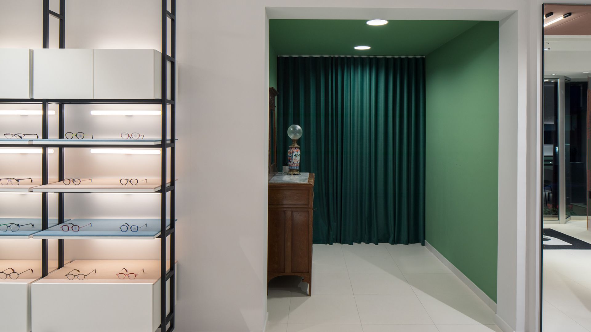 Una stanza con una tenda verde e uno scaffale con sopra dei bicchieri.