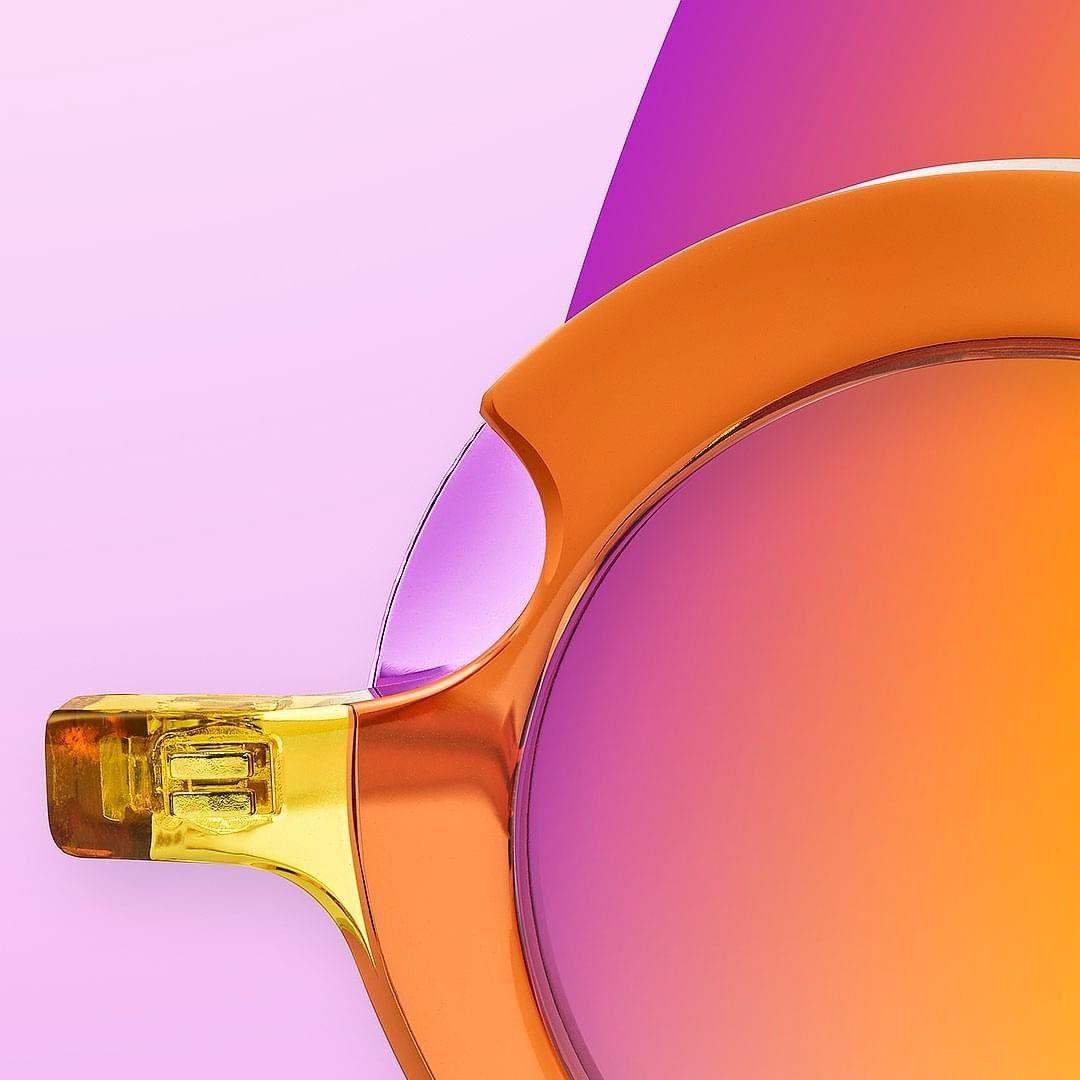 Un primo piano di un paio di occhiali da sole su uno sfondo viola e arancione