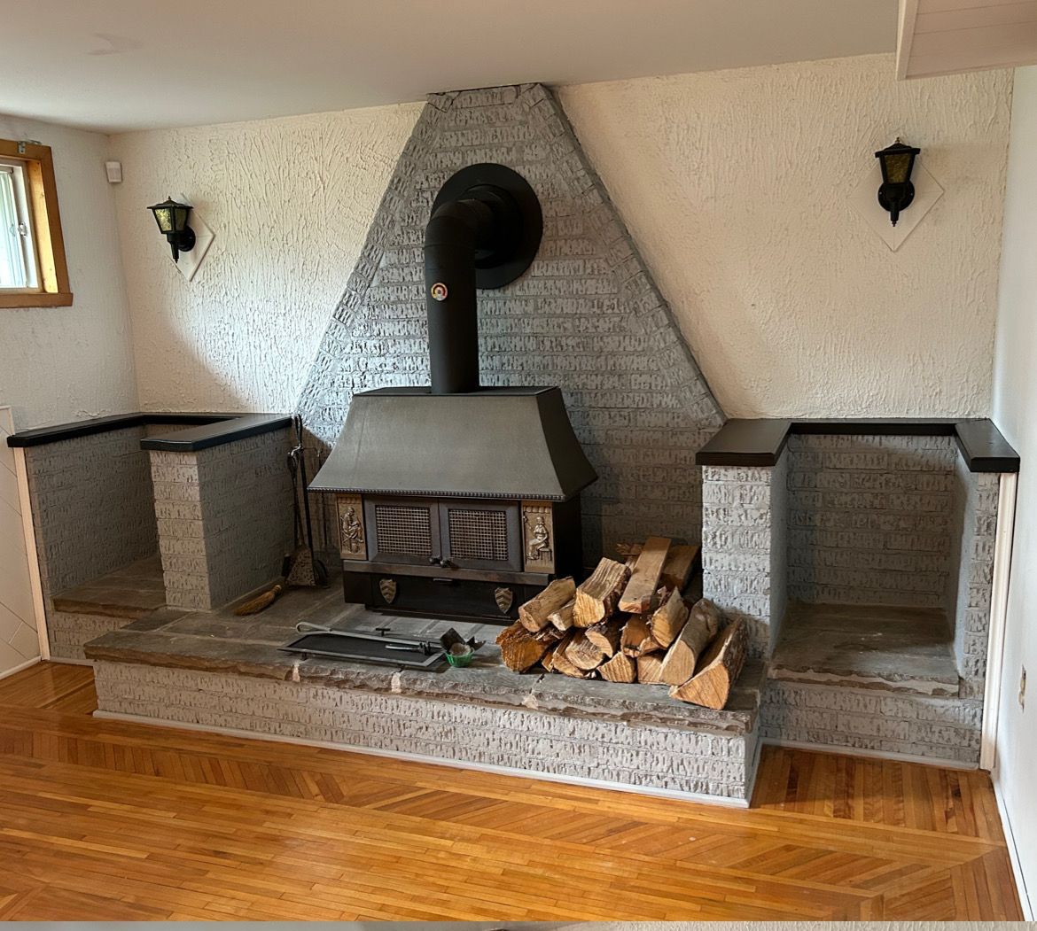 Cheminée avec entourage en briques, foyer, rangement pour le bois et appliques décoratives.