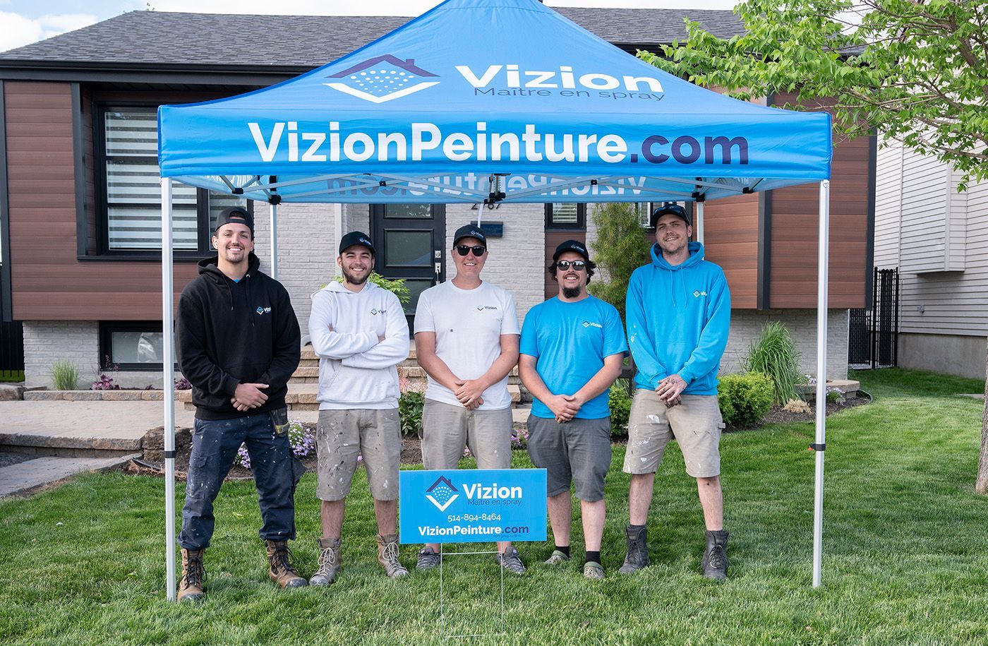 Cinq personnes devant une maison, sous une tente de marque. Le site web est « VizionPeinture.com ».